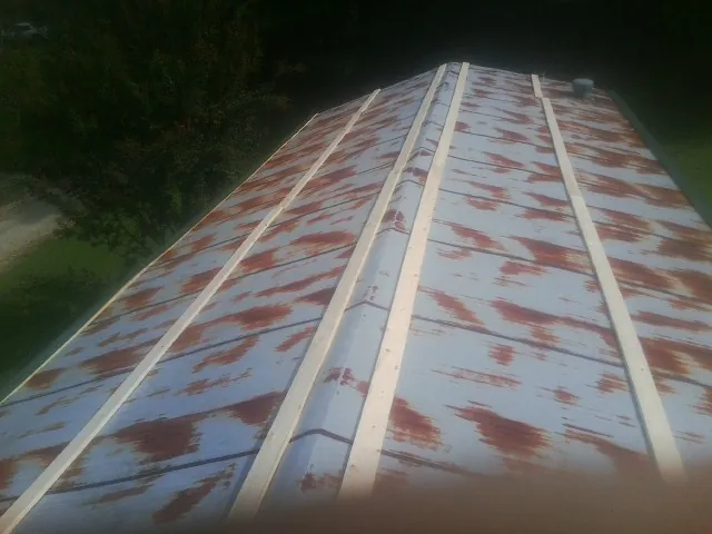 Rusted metal roof panels with new wood purlins before replacement in Tekamah