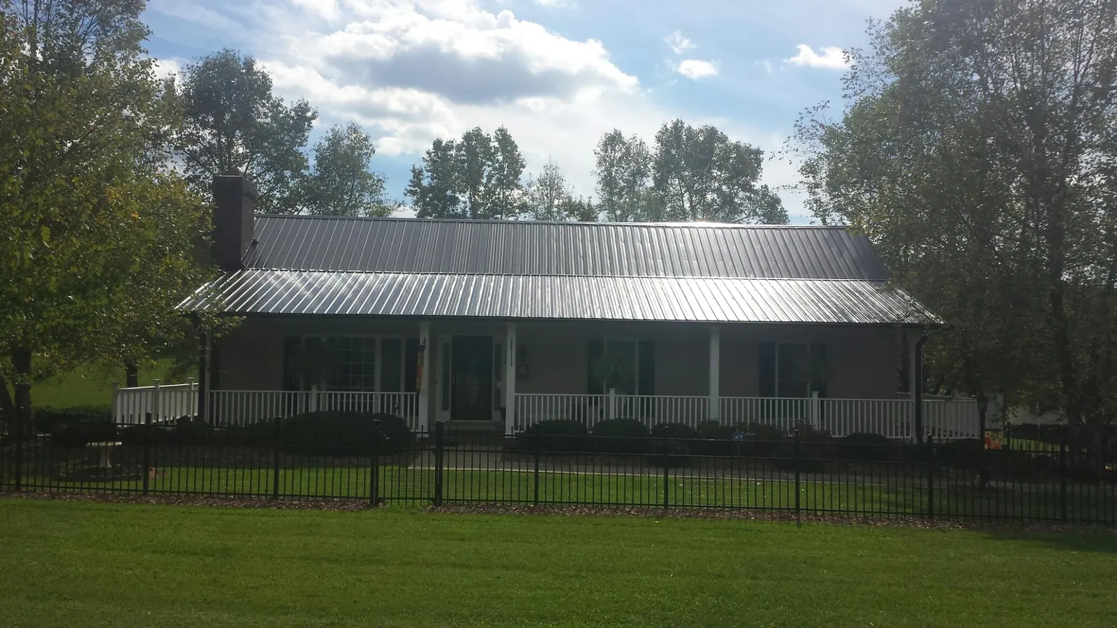 Gray metal roof on a brick ranch with a full width front porch — Gutter Guard Installation work by our crew in Tekamah