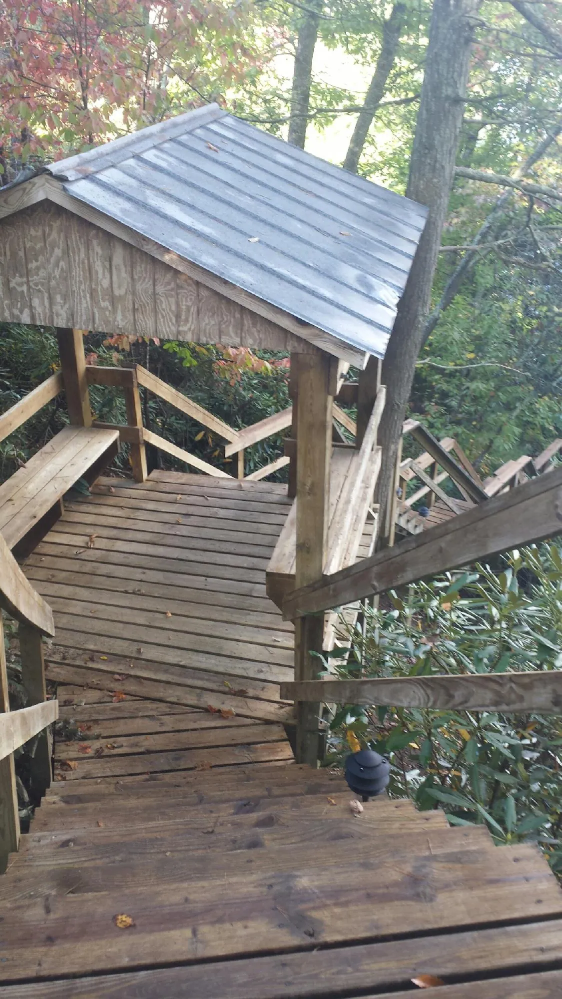 Metal roofed shelter over wooden steps on a wooded walkway — Skylight Repair & Installation work by our crew in Tekamah