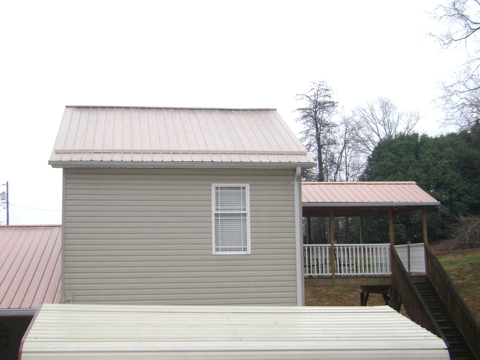 Tan metal roofs on a two story addition and attached porch, from a Roof Replacement job in Tekamah