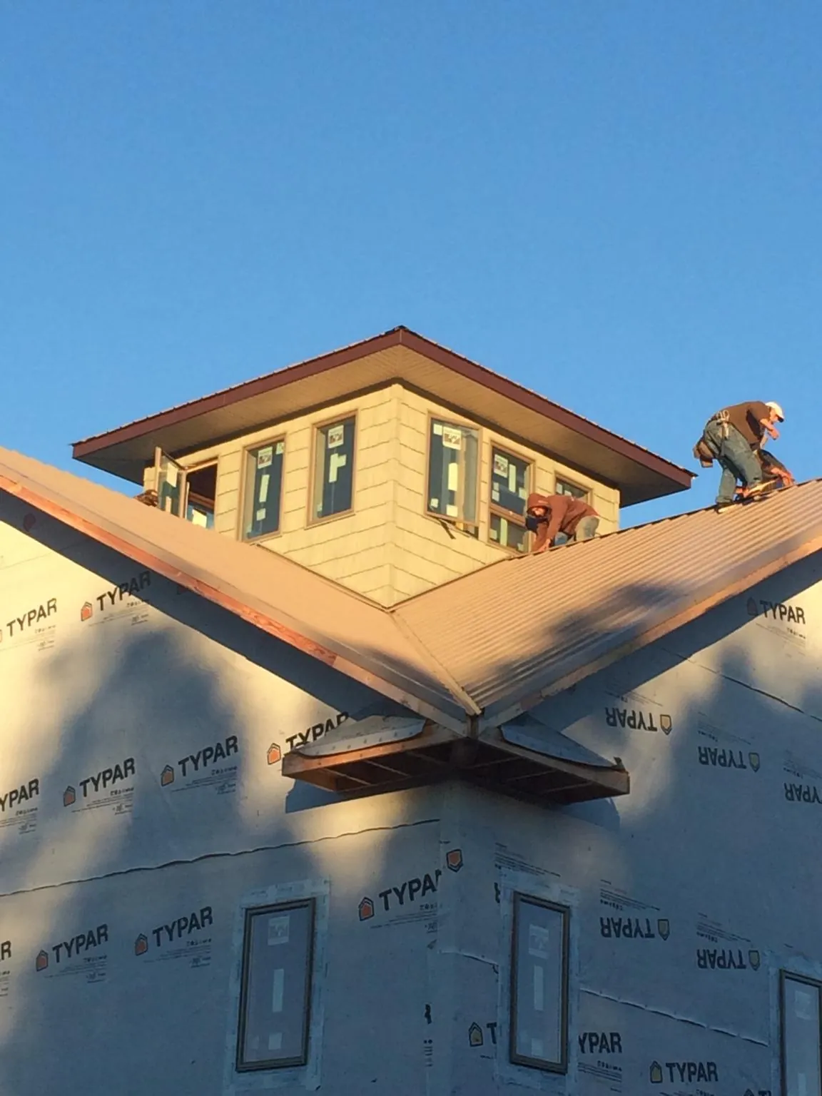 Roofers working around a rooftop cupola on a new metal roof at sunset — Roof Waterproofing in Tekamah by Roofing Brothers